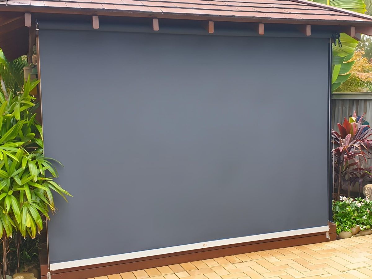 Ozrite cable guided outdoor blind with dark grey privacy fabric on a veranda for stronger evening privacy and outdoor comfort