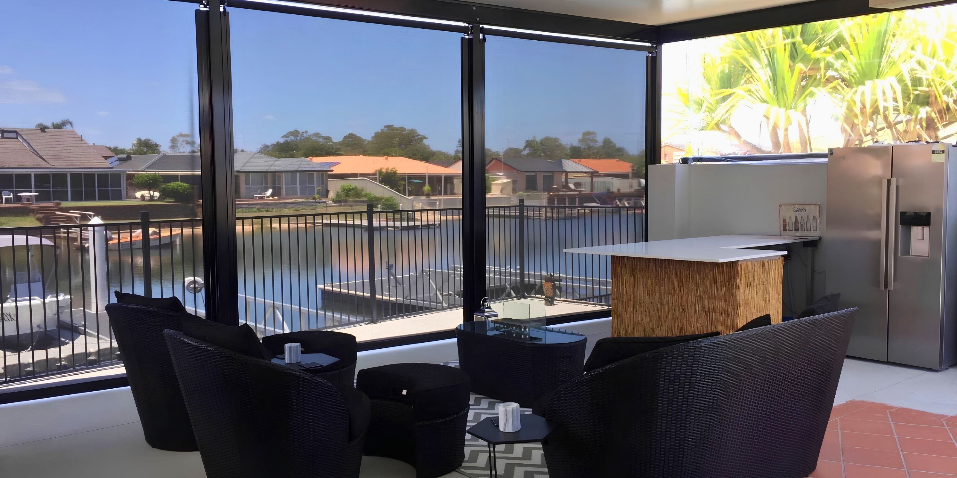 Custom DIY HD Channel outdoor blinds installed on a modern backyard patio to create a fully enclosed outdoor room looking out to the water.