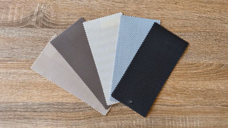 Step 2 of the Ozrite DIY outdoor blinds guide – fabric swatches in multiple colours on a wooden surface for comparing styles.