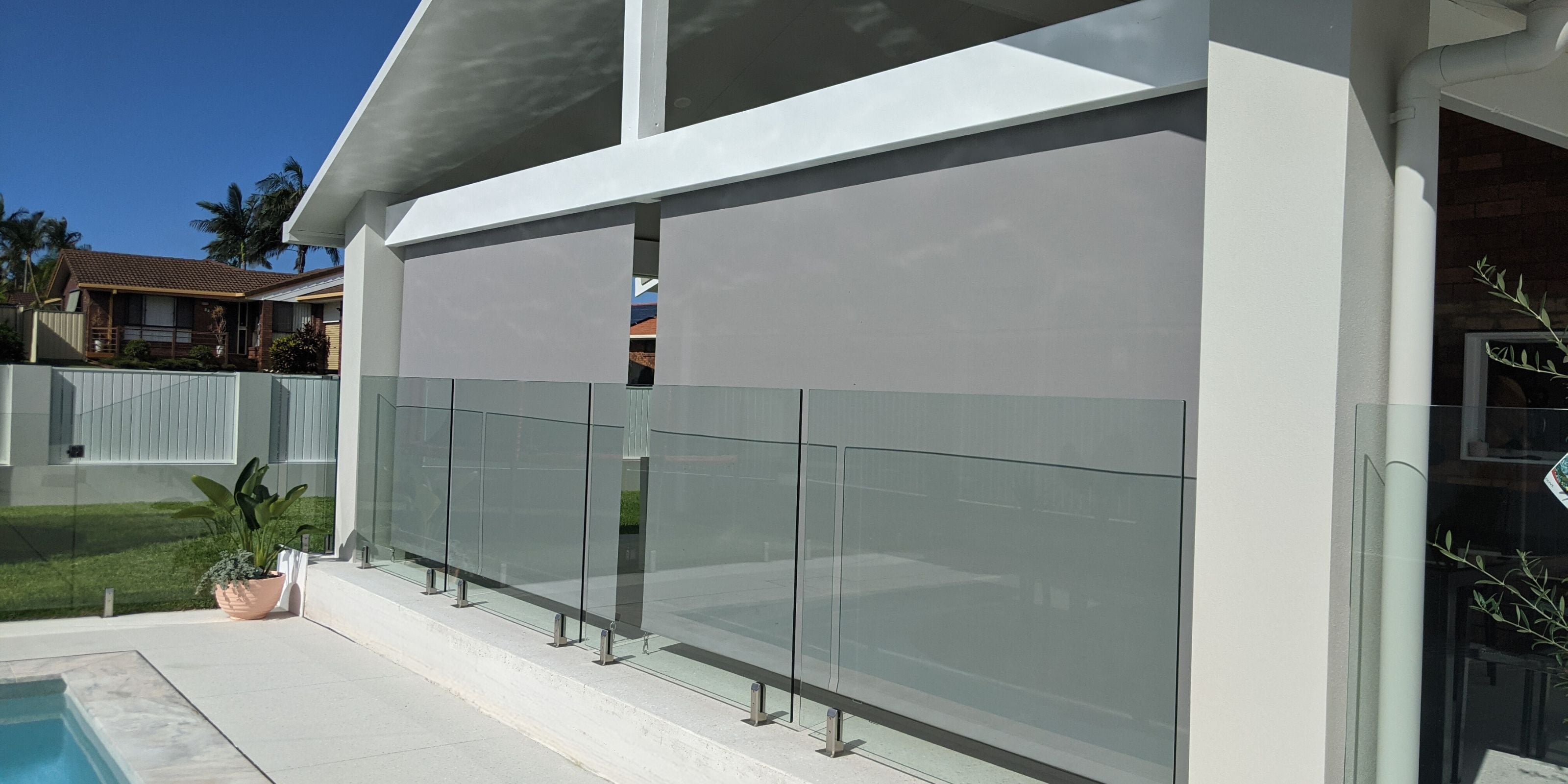 Modern outdoor blinds by Ozrite installed poolside, providing shade, privacy, and year-round protection.