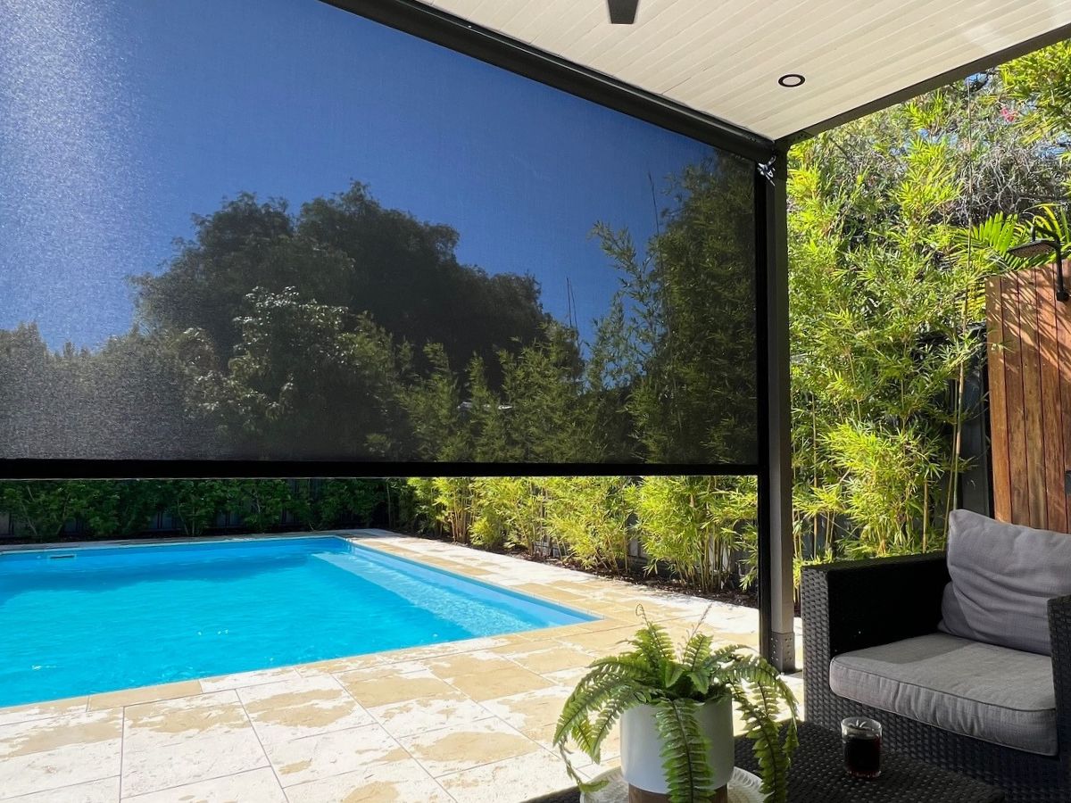 Ziplock outdoor blind installed on a covered poolside patio with garden views, providing sun and privacy protection.