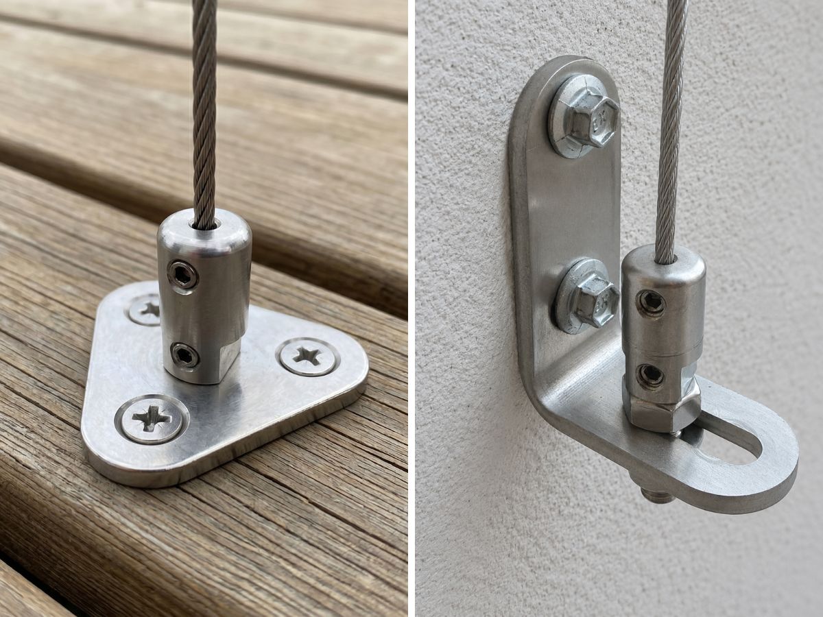 Close-up of a premium cable-guided outdoor blind wire system anchored with a stainless steel marine-grade deck plate and hex screws down into a concrete floor underneath a window.